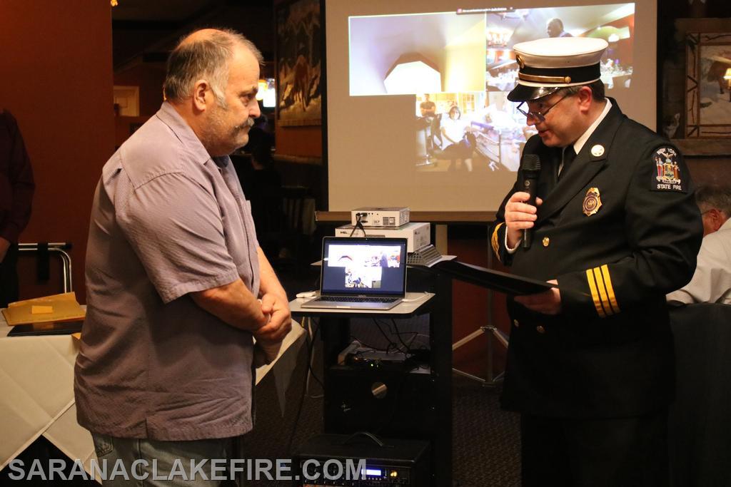 Kent Robinson is being recognized for 50 years as a volunteer firefighter by Ben Wheeler of the New York State Office of Fire Prevention and Control