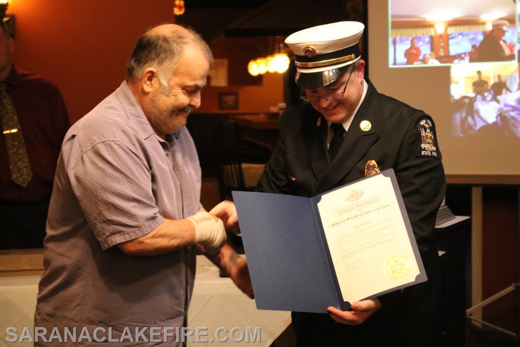 Kent Robinson is being recognized for 50 years as a volunteer firefighter by Ben Wheeler of the New York State Office of Fire Prevention and Control