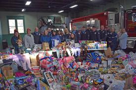 Holiday Helpers volunteers pose with members of the Saranac Lake Volunteer Fire Department, Saranac Lake Volunteer Rescue Squad and SLVFD Ladies’ Auxiliary at the end of the helpers’ toy drive at the firehouse on Saturday. (Enterprise photo — Aaron Marbone)