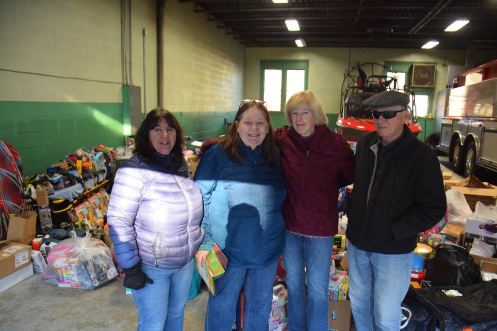 Holiday Helpers organizers, from left, Dawn Rogers and Patti Ploof pose with donors, Bobbie Frederick, in red, and Robin Smith at the end of the annual toy drive on Saturday. (Enterprise photo — Aaron Marbone)