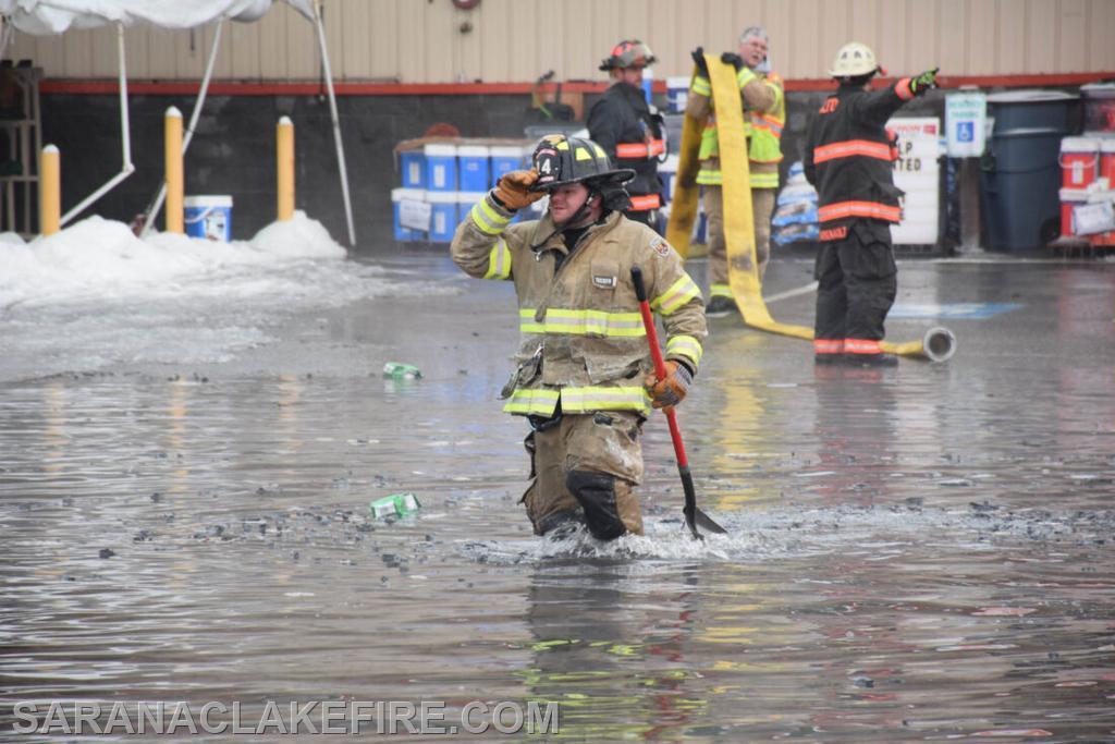 A firefighter wades in nearly knee-deep water in the Saranac Lake Aubuchon Hardware parking lot on Wednesday morning as firefighters from around 12 departments in Franklin, Essex and Clinton counties battle a massive fire at the Consolidated Electrical Distributors-Twin Electric Supply and ADK Solar building. (Enterprise photo — Aaron Marbone)